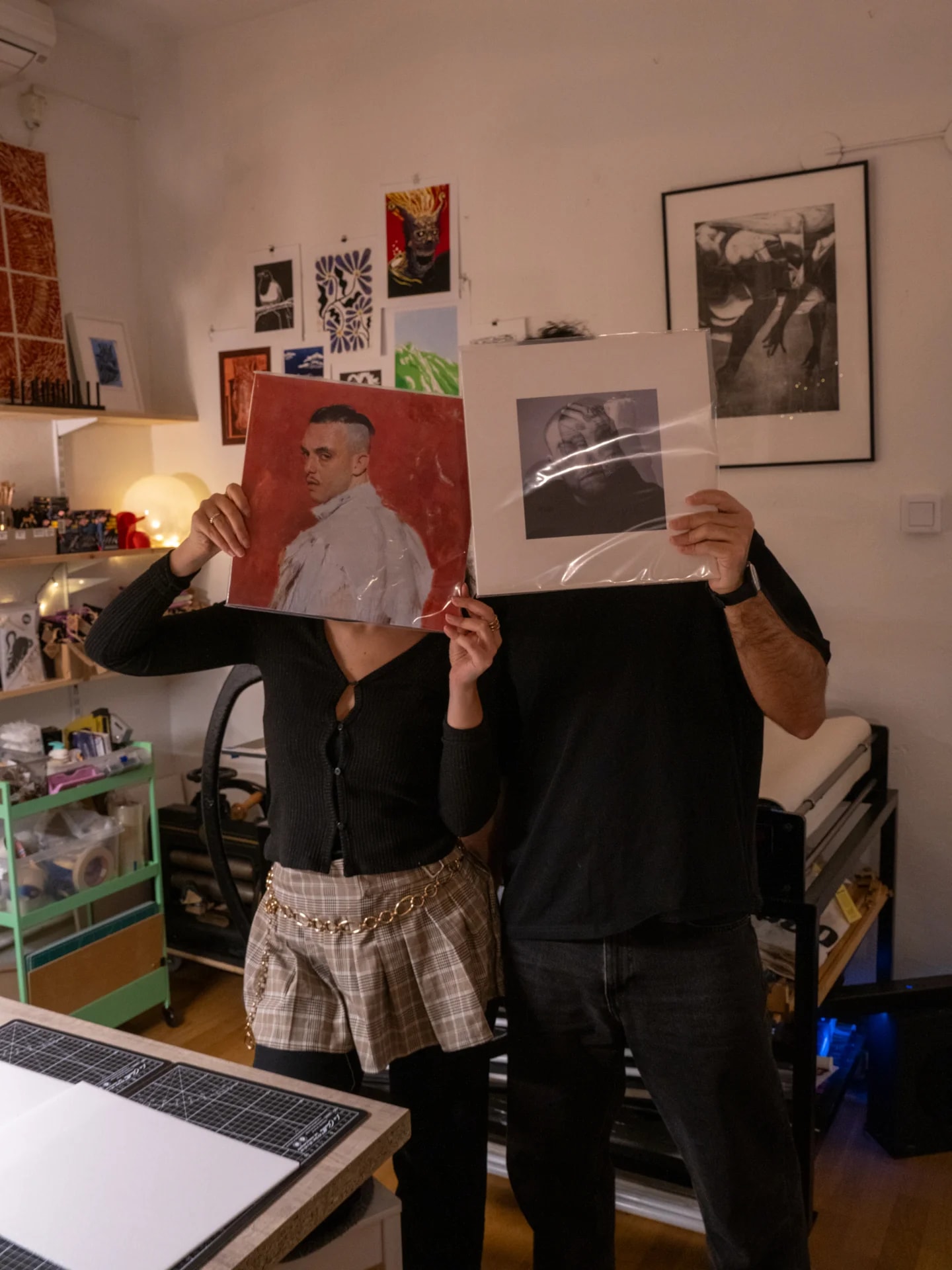 Two people holding up vinyl covers as inspiration in an art studio