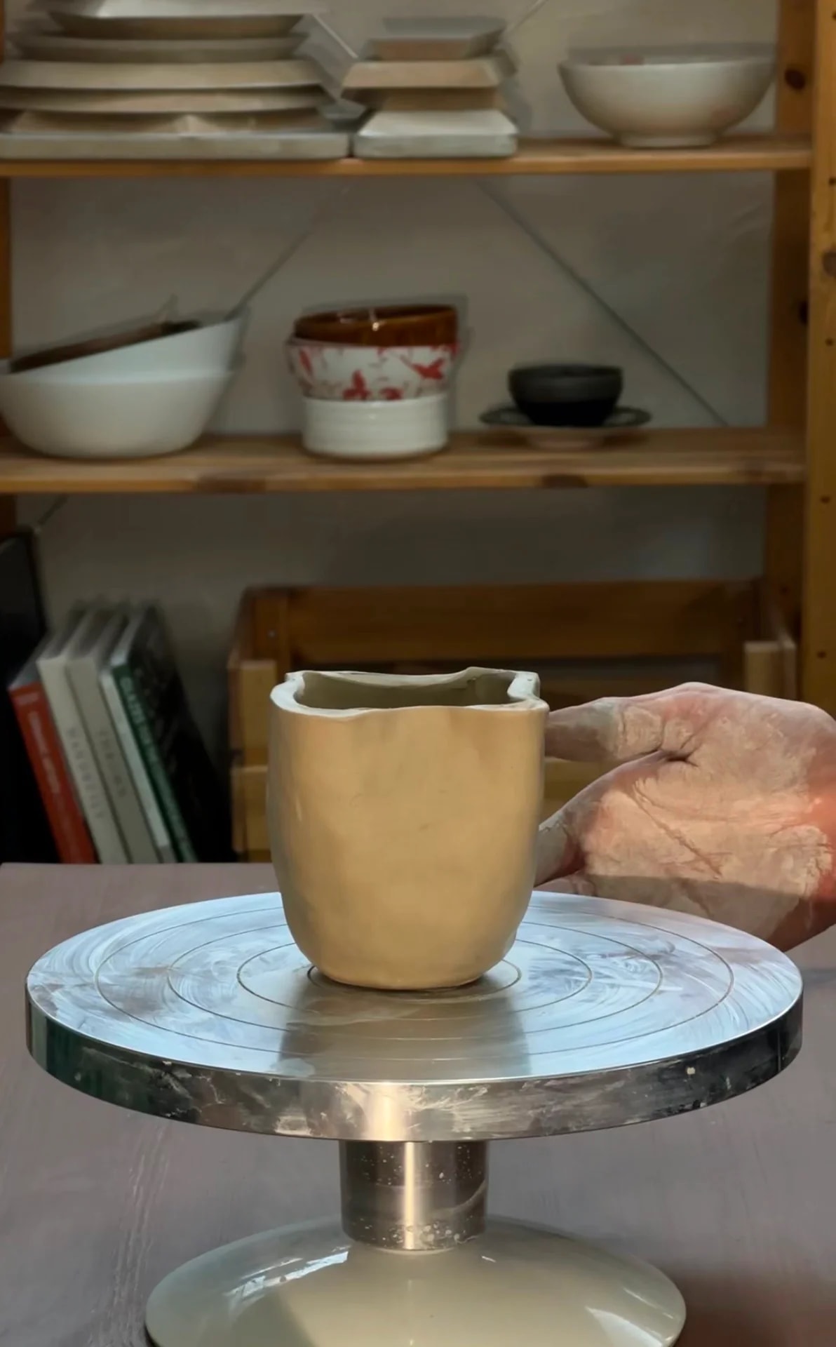 Hand-shaped clay cup on a pottery turntable