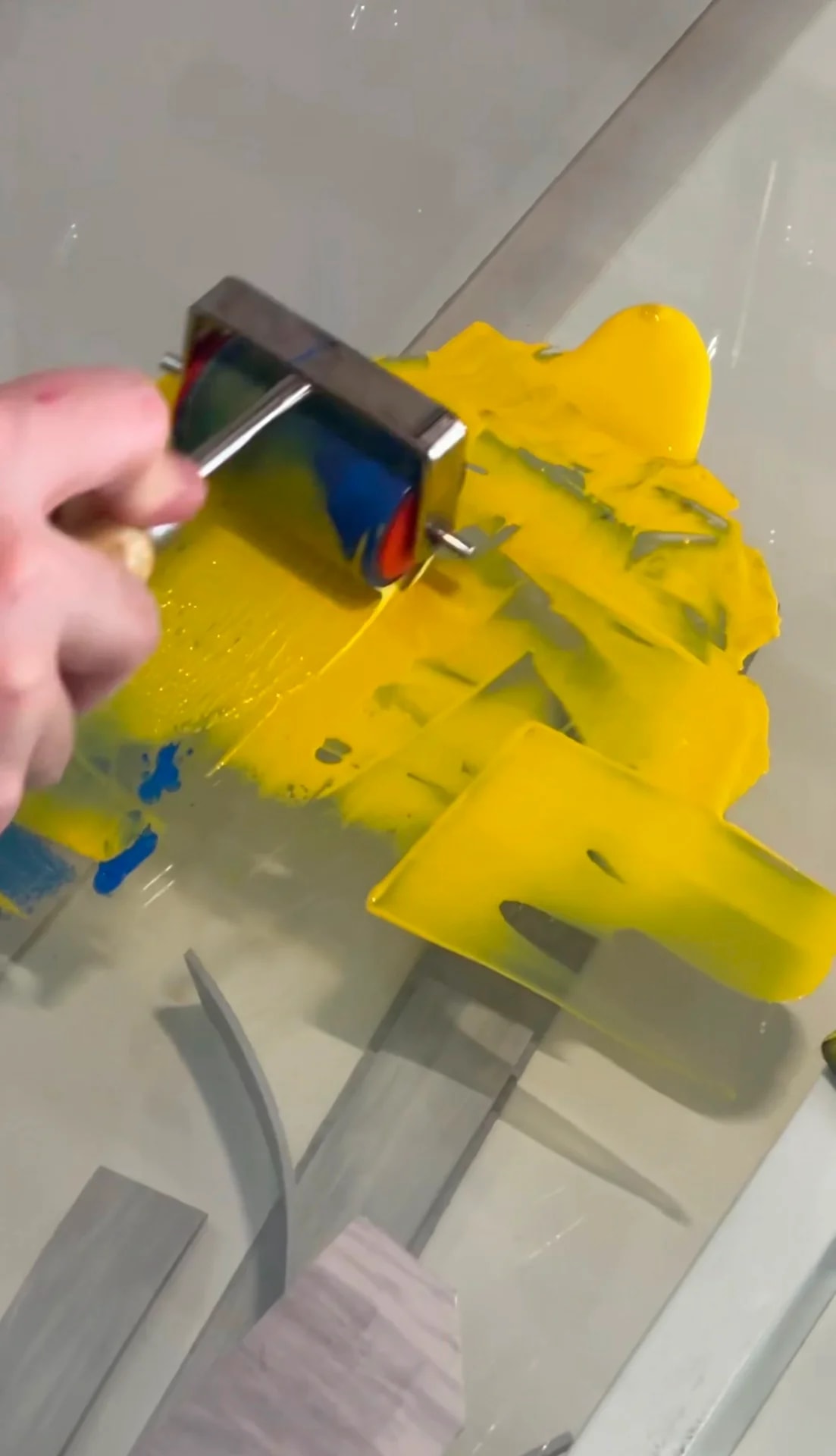 Rolling yellow ink on a glass surface for a print workshop