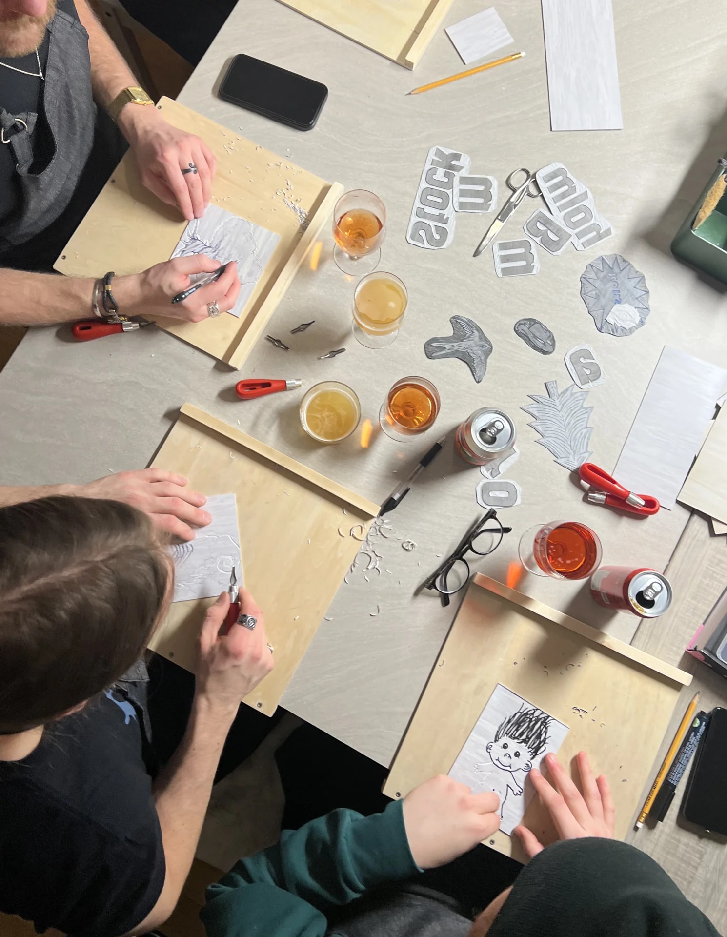 People carving lino blocks at a printmaking workshop table