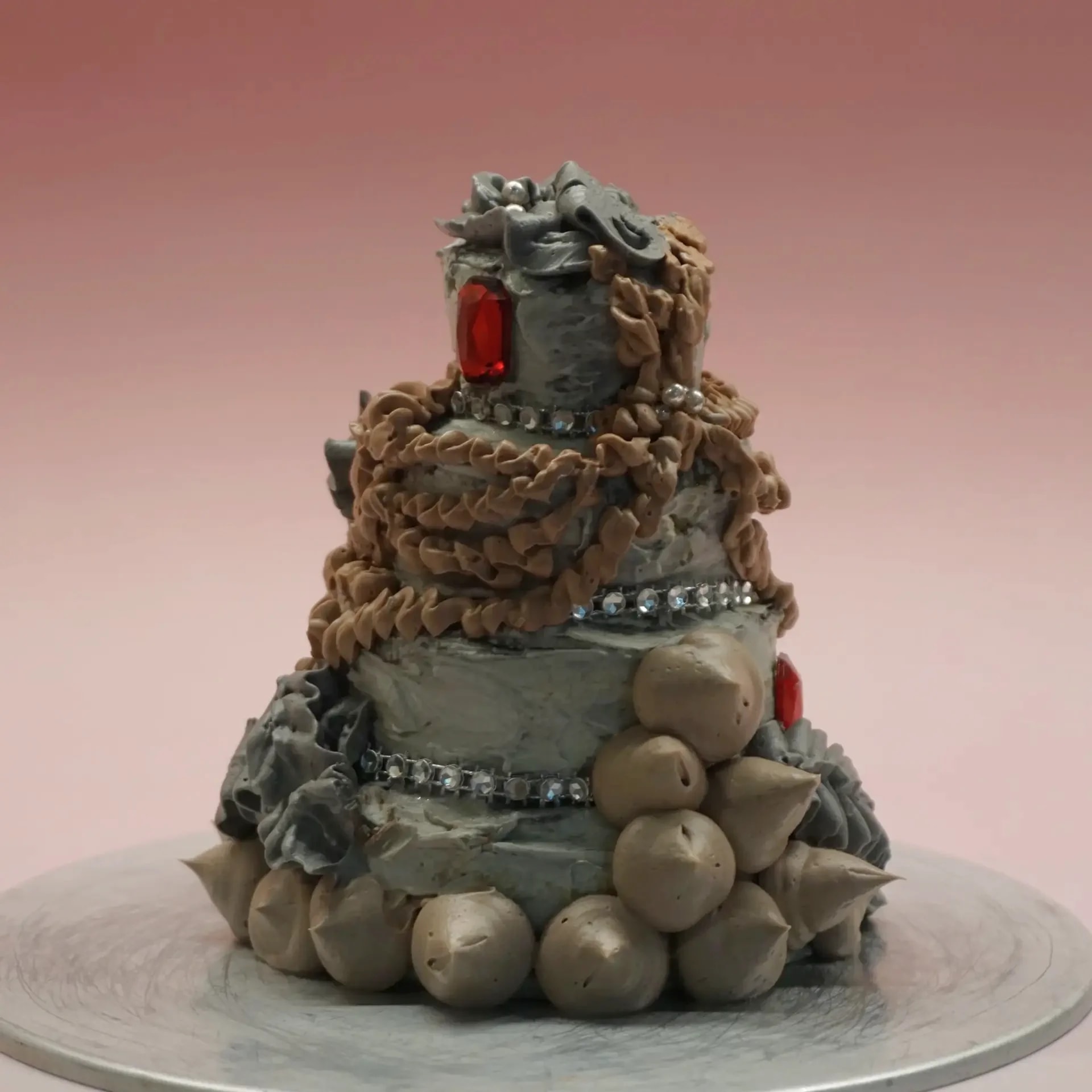 Decorated three-tier cake with piped frosting and gemstones